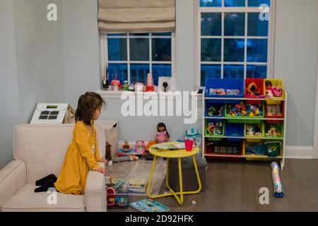 Kleines Mädchen spielt in ihrem bunten Spielzimmer in der Nacht Stockfoto