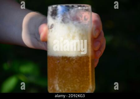 Hände halten Gläser mit Bier auf einem Tisch im Pub Open Cafe. Ein Mädchen und Freunde genießen Bier Zeit in der Stadt, aus der Nähe auf den Gläsern. Stockfoto