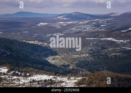 Schneebedeckter Berg mit Bäumen und Dorf unten Stockfoto