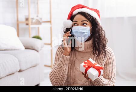 Schwarze Dame In Maske Gespräch Am Telefon Holding Geschenk Stockfoto