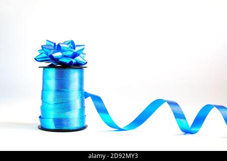Spule aus blauem gewelltem Band und dekorativer Geschenkschleife Weißer Hintergrund Stockfoto