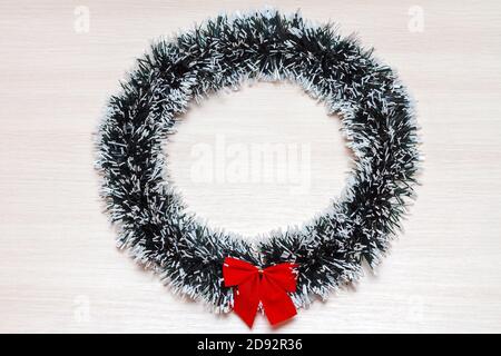 Weihnachtskranz mit roter Schleife auf beigem Holzhintergrund. Platz kopieren, Draufsicht Stockfoto