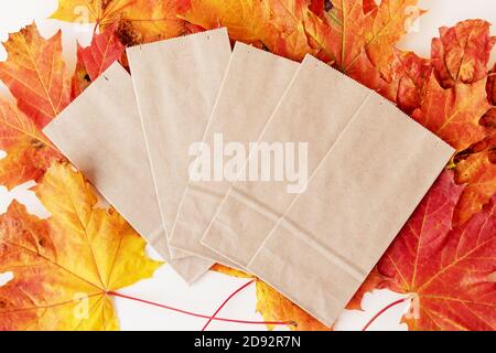 Leeren Sie die Papiertüten auf dem Stapel der trockenen Herbstblätter auf Weiß Stockfoto