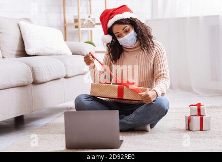 Schwarze Dame In Maske Öffnen Present Box Und Mit Laptop Stockfoto