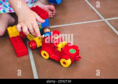 Ein einziges Kind spielt mit Duplo-Spielzeugen, Figuren und Fahrzeugen Stockfoto