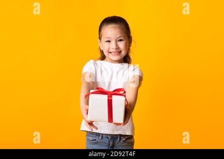 Glücklich asiatische Mädchen geben Sie Geschenk-Box bei orange Studio Stockfoto