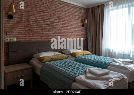 Leeres Hotelzimmer mit Betten in der Nähe der roten Backsteinmauer und Angezeigt Stockfoto