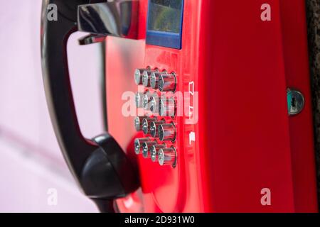 Rotes Straßentelefon mit runden Edelstahlknöpfen in Nahaufnahme. Eine veraltete Art der Kommunikation. Stockfoto