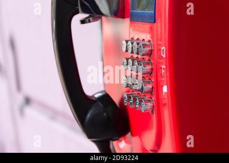 Rotes Straßentelefon mit runden Edelstahlknöpfen in Nahaufnahme. Eine veraltete Art der Kommunikation. Stockfoto