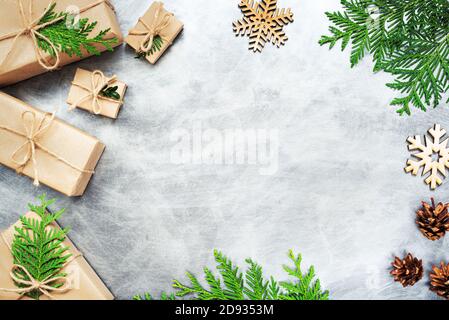 Zero Waste Weihnachten flach lag. Geschenkschachteln mit Kraftpapier, Tannenzweigen, hölzernen Schneeflocken, Zapfen auf grauem Hintergrund eingewickelt. Umweltfreundlicher Urlaub. Stockfoto