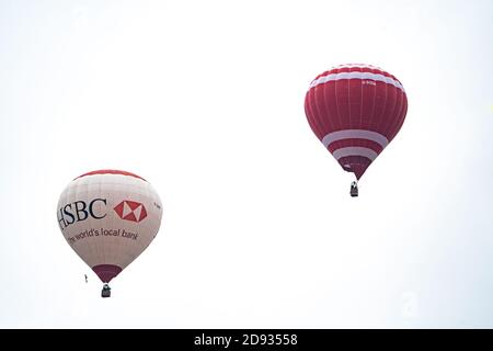 Zwei Heißluftballons vor einem weißen Himmel ohne Feature, einer mit HSBC Bank Livery, Großbritannien Stockfoto