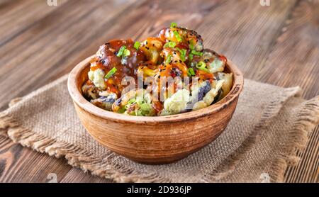 Schüssel mit asiatischen gebratenen Blumenkohl auf rustikalem Hintergrund Stockfoto