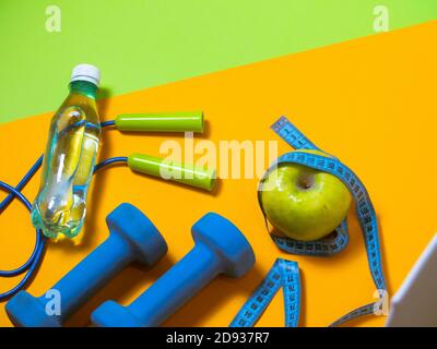 Flachbild von Fitnessgeräten über orangefarbenem und grünem Hintergrund. Draufsicht Stockfoto