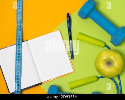 Flachbild von Fitnessgeräten über orangefarbenem und grünem Hintergrund. Draufsicht Stockfoto