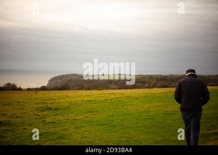 Ein alter Mann, der durch die Feuereichs in Fairlight, in der Nähe von Hastings, geht Stockfoto