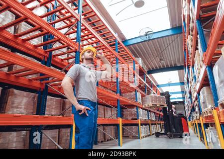 Logistikmitarbeiter, der im Hochregallager steht Stockfoto