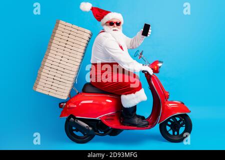 Ganzkörper-Profil Seitenfoto von weißen grauen Haaren bärtig santa claus Antrieb Motorrad Reise Weihnachten Heiligabend Haufen Pizza tragen roten Hut Kostüm Stockfoto
