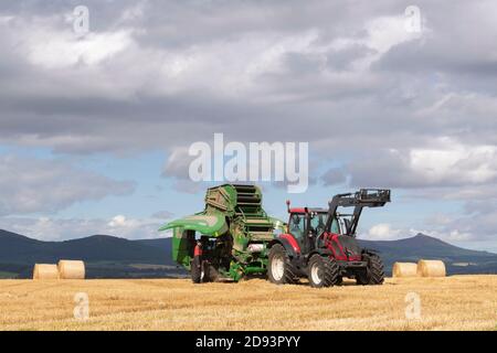 Ein Landwirt Reinigung einer McHale Ballenpresse nach Gebrauch mit dem Menaway Hills und Bennachie in the Distance Stockfoto