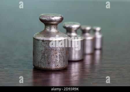 Ein Satz von alten zerkratzten Eisengewichten für eine Apothekenwaage. Stockfoto