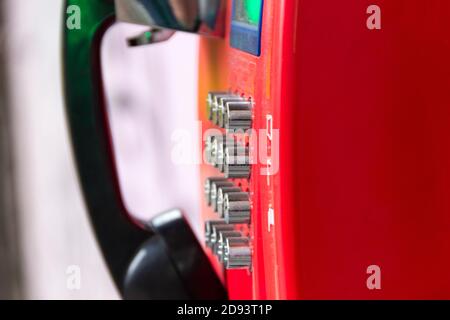 Rotes Straßentelefon mit runden Edelstahlknöpfen in Nahaufnahme. Eine veraltete Art der Kommunikation. Stockfoto