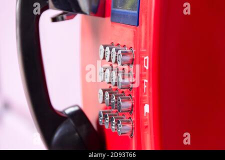 Rotes Straßentelefon mit runden Edelstahlknöpfen in Nahaufnahme. Eine veraltete Art der Kommunikation. Stockfoto