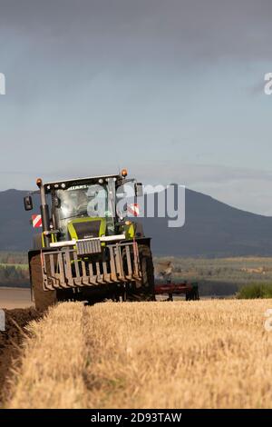 Ein Claas Traktor pflügt ein Stoppeln Feld auf einem Sunny Nachmittag in Rural Aberdeenshire Stockfoto