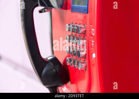 Rotes Straßentelefon mit runden Edelstahlknöpfen in Nahaufnahme. Eine veraltete Art der Kommunikation. Stockfoto