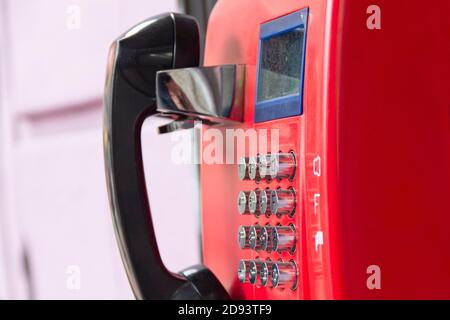 Rotes Straßentelefon mit runden Edelstahlknöpfen in Nahaufnahme. Eine veraltete Art der Kommunikation. Stockfoto