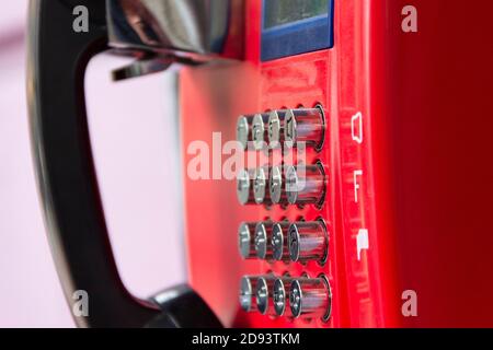 Rotes Straßentelefon mit runden Edelstahlknöpfen in Nahaufnahme. Eine veraltete Art der Kommunikation. Stockfoto