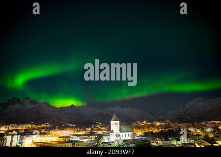 Tanzende grüne Polarlichter über der Stadt Svolvaer auf der Lofoten Inseln in Norwegen bei Nacht im Winter mit Schnee