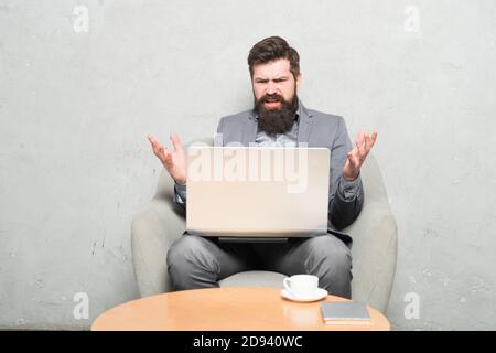 Probleme bei der Arbeit. Hipster Kaffee trinken und Arbeiten am Computer Arbeitsplatz. Bärtiger Mann seine Arbeit online tun. Weltweit arbeiten durch Abstand arbeiten. Stockfoto