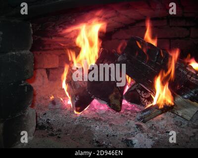 Brennholz brennt in der Mündung des russischen Ofens. Schöne orange helle Flamme. Das Feuer brennt im Ofen. Stockfoto