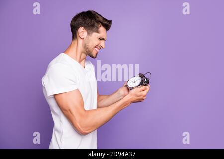Profil Seitenansicht Porträt von seinem er schön attraktiv gereizt Wütend braunhaarige Kerl hält in der Hand Uhr Wake up früh isoliert Auf hellen lebendigen Glanz Stockfoto