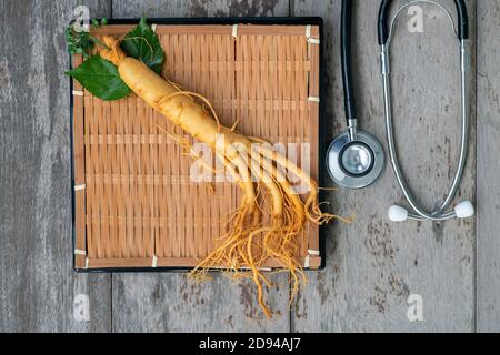 Frischer Ginseng Bambuskorb mit Stethoskop auf dem Holzhintergrund Stockfoto