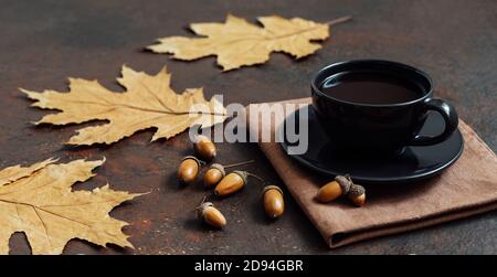 Stillleben mit einer Tasse Kaffee, trockenen Blättern und Eicheln auf braunem Hintergrund. Acorn-Kaffee. Ein Ersatz für Kaffee. Seitenansicht. Stockfoto