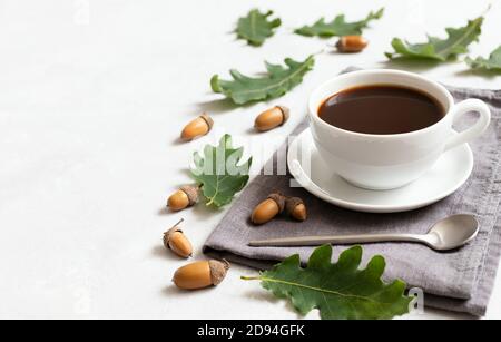 Schwarzer Kaffee mit einem Muster aus Eichenblättern und Eicheln auf weißem Hintergrund. Acorn-Kaffee. Leerzeichen für Text. Koffeinfrei. Stockfoto