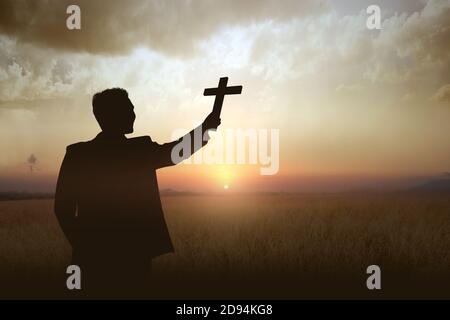 Silhouette eines Geschäftsmannes mit christlichem Kreuz und Sonnenuntergang Himmel Hintergrund Stockfoto