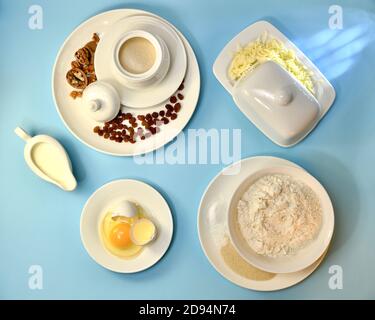 Mehl Butter zerbrochene Ei Milch Zucker Hefe Salz Backpulver Rosinen Walnüsse, auf einem hellblauen Hintergrund. Stockfoto