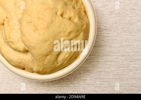 Gelber Teig in einer Schüssel leben. Der abschließende Gärungsprozess. Stockfoto