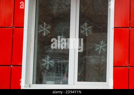 Weihnachtliche Dekoration am Fenster aus künstlichen Schneeflocken Stockfoto