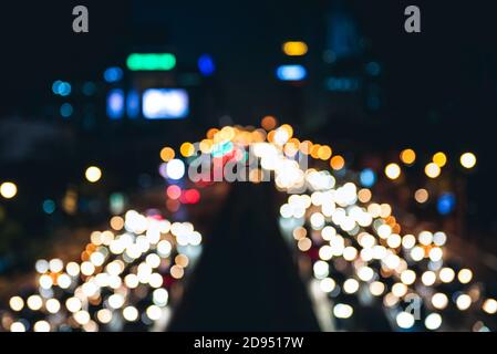 Verschwommener Blick auf die Straße von Bangkok bei Nacht mit lebhaftem Licht von Autos und Gebäuden, Bokeh Hintergrundkonzept Stockfoto