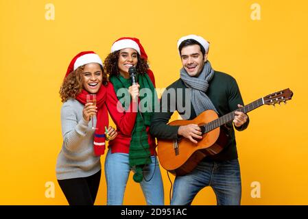 Fröhliche, vielfältige Freunde, die Party singen und Weihnachten feiern Auf gelbem isoliertem Hintergrund Stockfoto