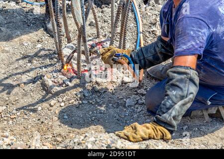 Arbeiter schneiden Beton Stahlstäbe mit Fackel auf der Baustelle. Stockfoto