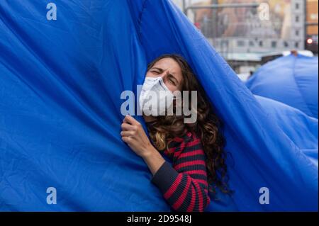 Während der Demonstration ist ein Aktivist mit Gesichtsmaske im blauen Tuch zu sehen.während der dritten internationalen Rebellion blockierte die Bewegung Extinction Rebellion die Gran Vía Straße in Madrid, um gegen die Folgen des steigenden Meeresspiegels zu protestieren. Die Bewegung, die ein 150 Quadratmeter blaues Tuch vom Callao-Platz zum spanischen Platz trägt, marschiert über die Gran Vía-Straße, um die wachsende Zahl der Menschen sichtbar zu machen, die vom Anstieg des Meeresspiegels, verursacht durch den Klimawandel, betroffen sind. Dieser Akt unter dem Namen "Wir sinken" hat die große Zahl der Todesfälle durch den Anstieg des Meeresspiegels dargestellt. Stockfoto