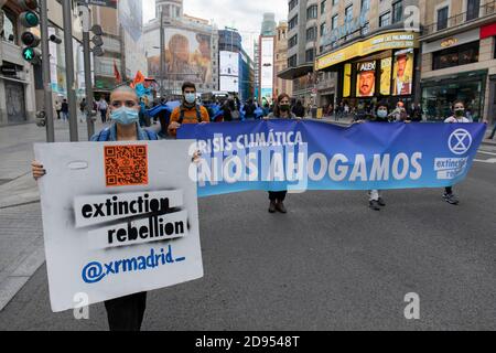Aktivisten mit Gesichtsmasken halten ein Banner mit der Aufschrift "Klimakrise, wir sinken während der Demonstration.während der dritten internationalen Rebellion blockierte die Bewegung "Extinction Rebellion" die Gran Vía Straße in Madrid, um gegen die Folgen des steigenden Meeresspiegels zu protestieren. Die Bewegung, die ein 150 Quadratmeter blaues Tuch vom Callao-Platz zum spanischen Platz trägt, marschiert über die Gran Vía-Straße, um die wachsende Zahl der Menschen sichtbar zu machen, die vom Anstieg des Meeresspiegels, verursacht durch den Klimawandel, betroffen sind. Dieser Akt unter dem Namen "Wir sinken" hat die große Zahl der Todesfälle durch den Anstieg des Meeresspiegels dargestellt. Stockfoto