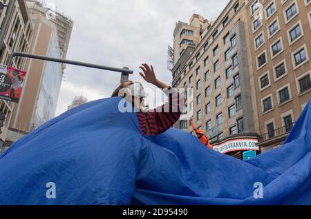 Während der Demonstration ist ein Aktivist mit Gesichtsmaske im blauen Tuch zu sehen.während der dritten internationalen Rebellion blockierte die Bewegung Extinction Rebellion die Gran Vía Straße in Madrid, um gegen die Folgen des steigenden Meeresspiegels zu protestieren. Die Bewegung, die ein 150 Quadratmeter blaues Tuch vom Callao-Platz zum spanischen Platz trägt, marschiert über die Gran Vía-Straße, um die wachsende Zahl der Menschen sichtbar zu machen, die vom Anstieg des Meeresspiegels, verursacht durch den Klimawandel, betroffen sind. Dieser Akt unter dem Namen "Wir sinken" hat die große Zahl der Todesfälle durch den Anstieg des Meeresspiegels dargestellt. Stockfoto