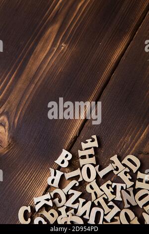 Buchstaben des englischen Alphabets auf dunklem Holzhintergrund. Das Konzept der Bildung, Wortspiele, Handarbeiten. Leerzeichen für Text Stockfoto