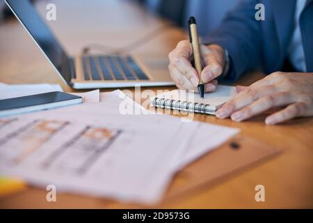 Arbeiterhänden schreiben auf Spiralnotizbuch Stockfoto