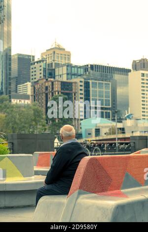 Melbourne, Australien - EIN einsamer alter Mann, der auf einer Bank im Zentrum von Melbourne sitzt Stockfoto