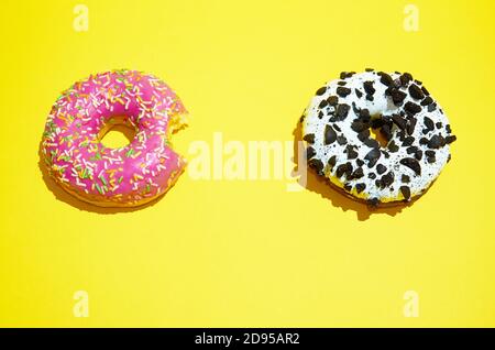 Rosa und weiße Donuts liegen auf einem gelben Hintergrund. Der Blick von oben Stockfoto